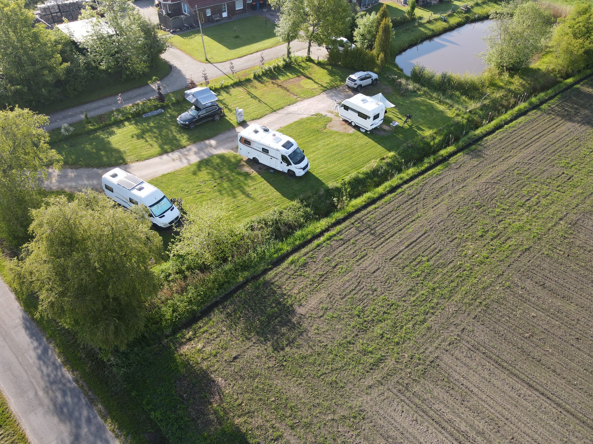 Luftaufnahme des Wohnmobilstellplatzes am Königsweg mit drei Stellplätzen zwischen Feld und Teich
